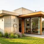 Comment réhabiliter une maison d’architecte grâce à une transformation réussie ? Maison d’architecte des années 1970 en rénovation, avec béton brut, grandes baies vitrées, extension contemporaine en bois et jardin lumineux.